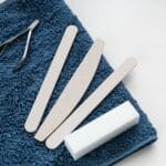 Zestaw narzędzi do manicure ułożony na miękkim błękitnym ręczniku